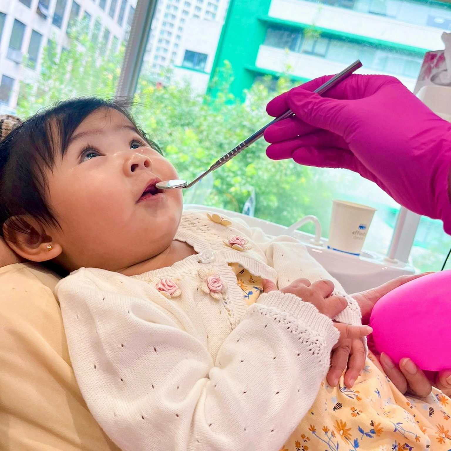Infant during her first dental check-up at Affinity Dental Clinics Makati, gently examined with a dental mirror by a pediatric dentist