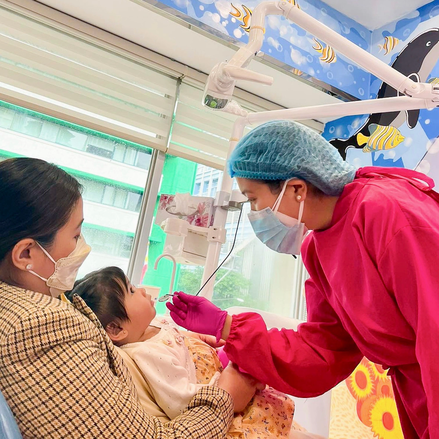 Dentist performing an infant’s first dental check-up at Affinity Dental Clinics Makati while the mother provides comfort during the visit