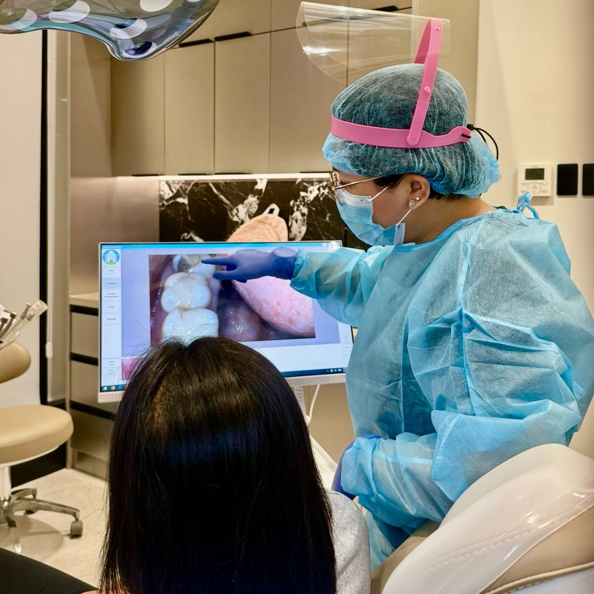 Dentist at Affinity Dental Clinics Parañaque showing a patient intraoral camera images of her teeth during consultation.