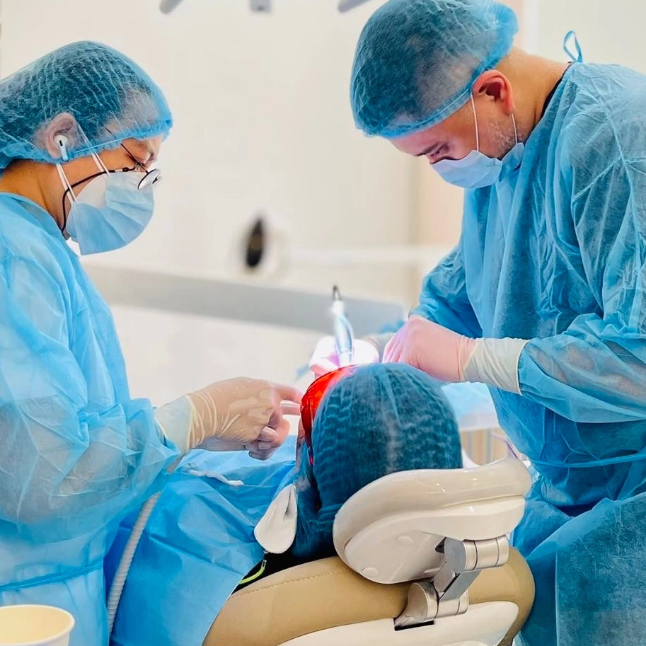 Oral surgeons in blue surgical gowns performing dental implant surgery at Affinity Dental Clinics BGC
