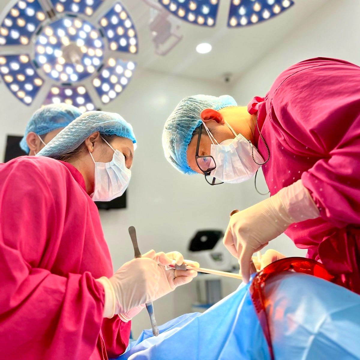 Oral surgeons performing dental implant surgery at Affinity Dental Clinics Makati operating room under surgical lights