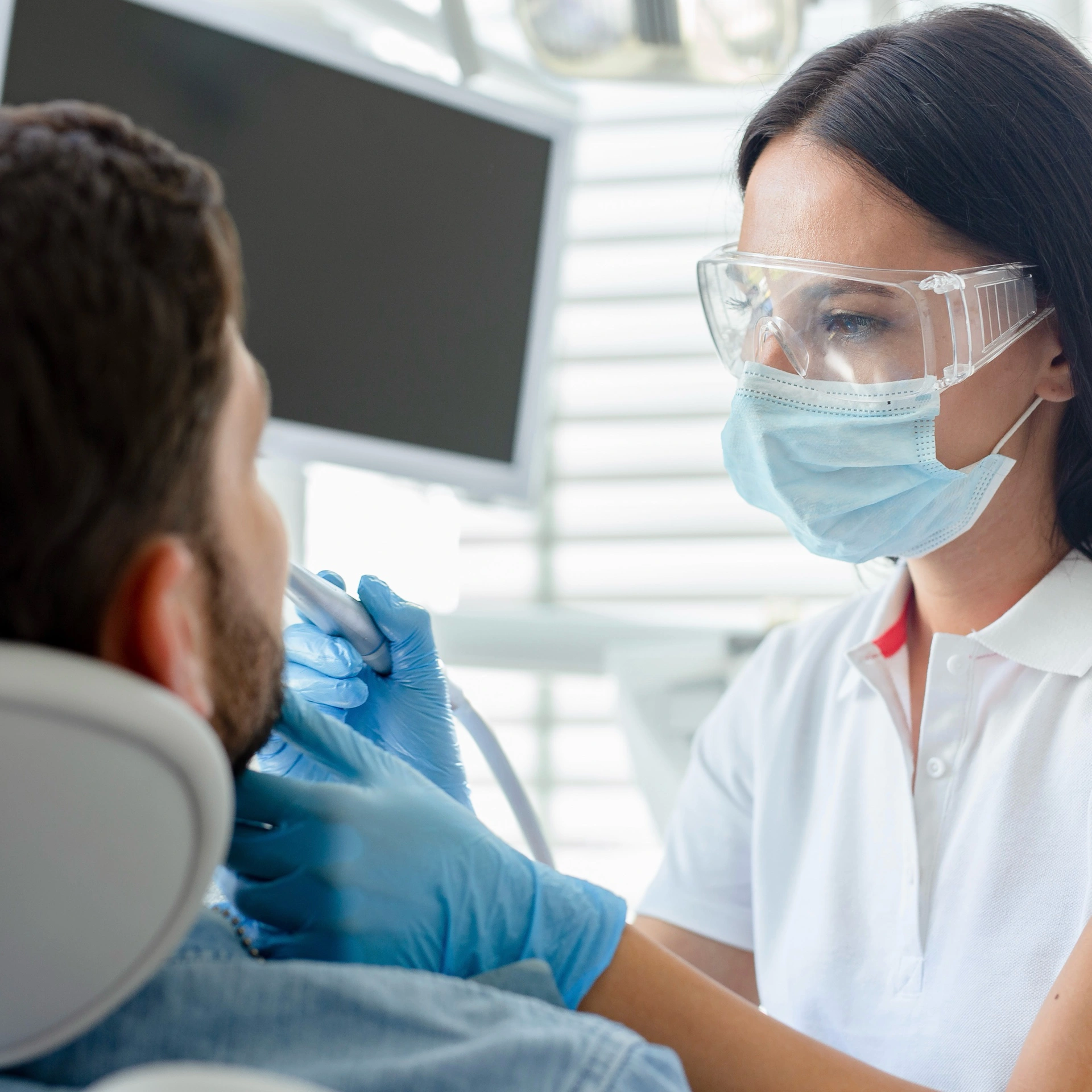 Dentist examining a male patient during a general dentistry appointment.