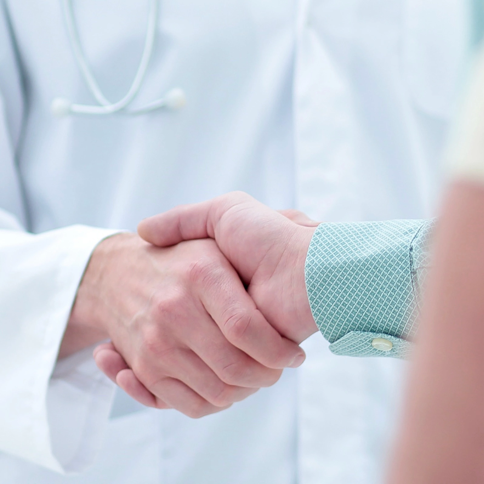 Close-up of a dentist and patient shaking hands, symbolizing trust and partnership in dental care.