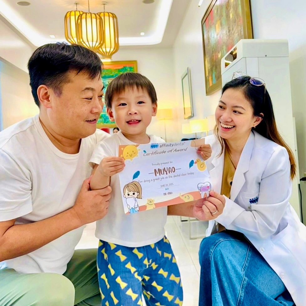 Dentist smiling with a young child holding a certificate of award after a pediatric dental consultation at Affinity Dental Clinics Makati