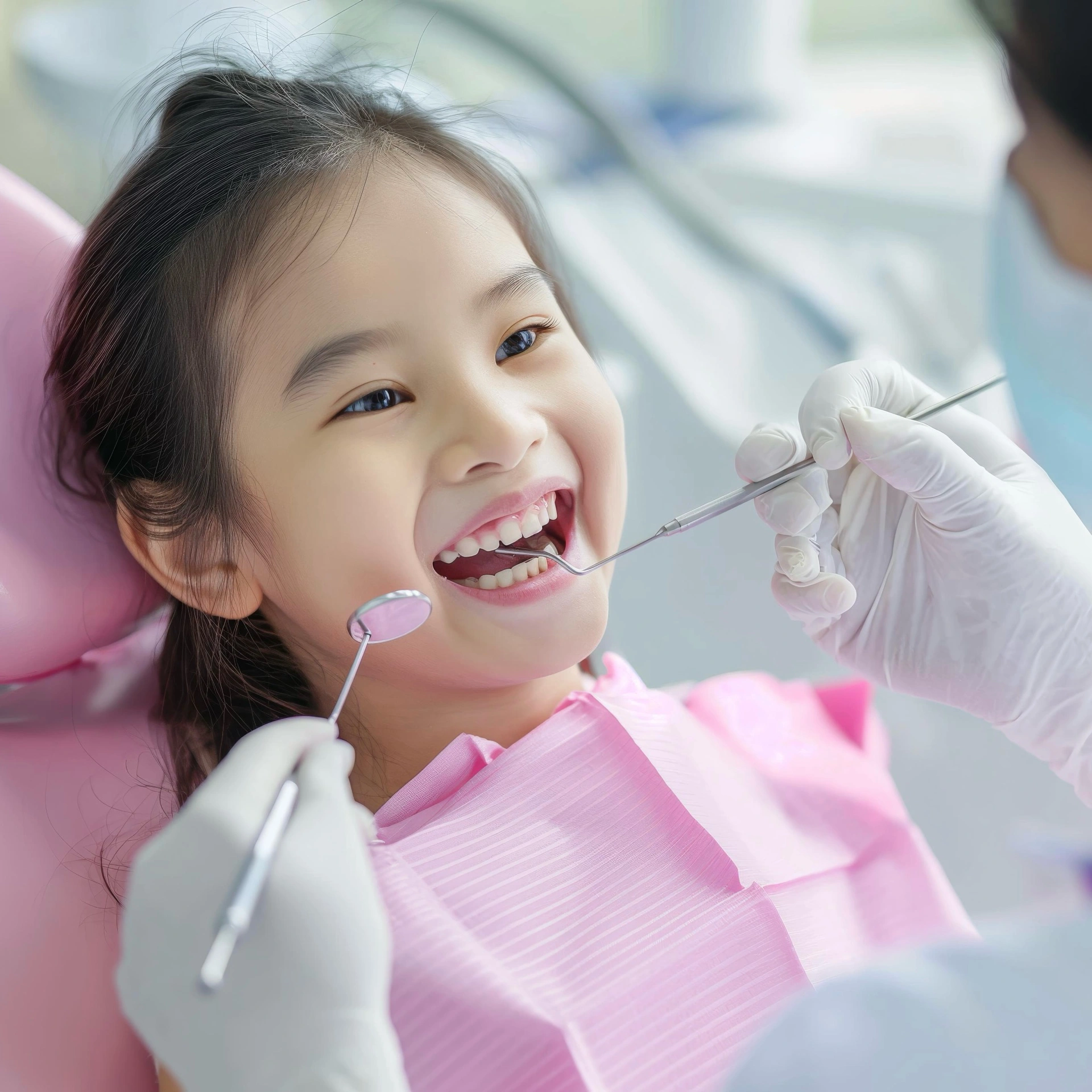 Young child smiling during a dental check-up with a pediatric dentist using dental instruments.