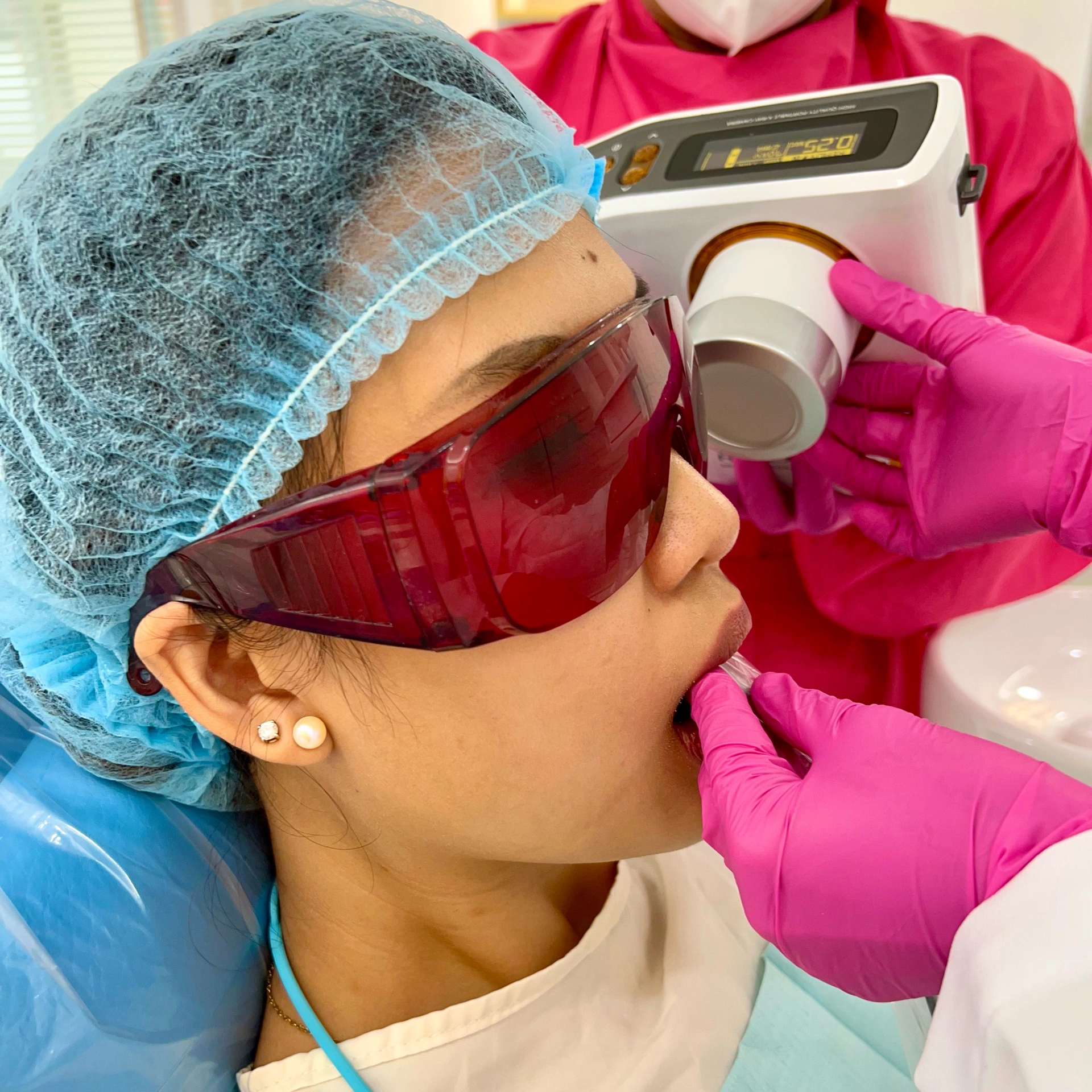 Dentist taking a periapical dental X-ray of a female patient at Affinity Dental Clinics using handheld digital X-ray equipment.
