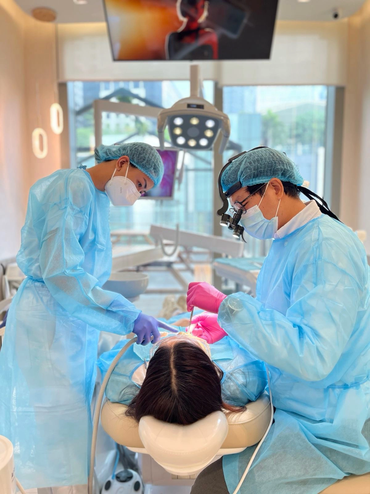 Dentists performing root canal treatment on a patient at Affinity Dental Clinics BGC High Street, wearing full protective gear in a modern dental operating room
