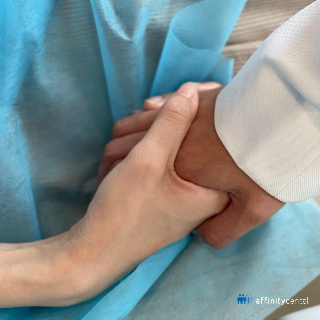 Close-up of a patient with dental anxiety holding a dentist’s hand while being placed under conscious sedation at Affinity Dental Clinics BGC High Street