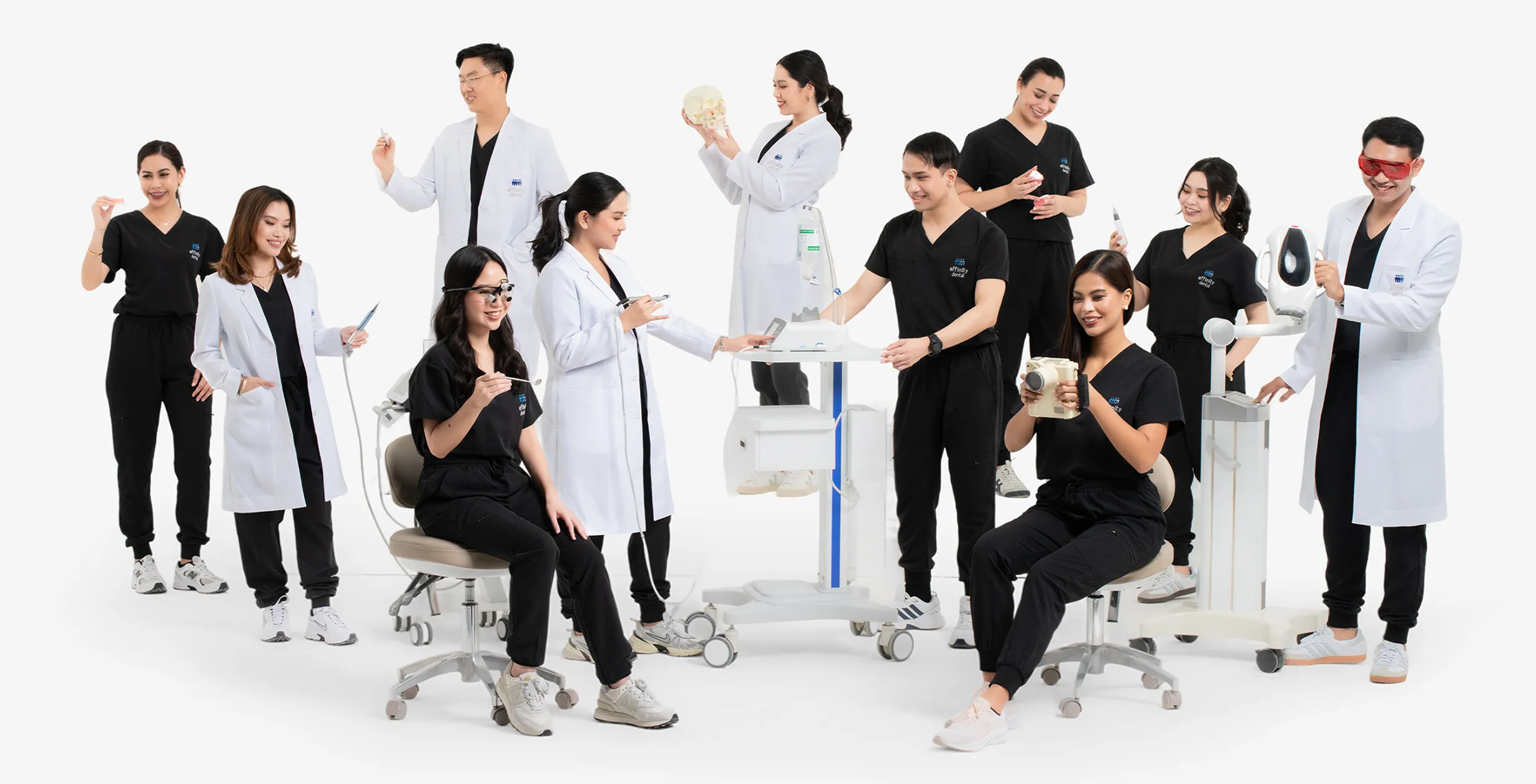 Affinity Dental Clinics dentists and specialists in black scrubs and white coats holding dental models and instruments