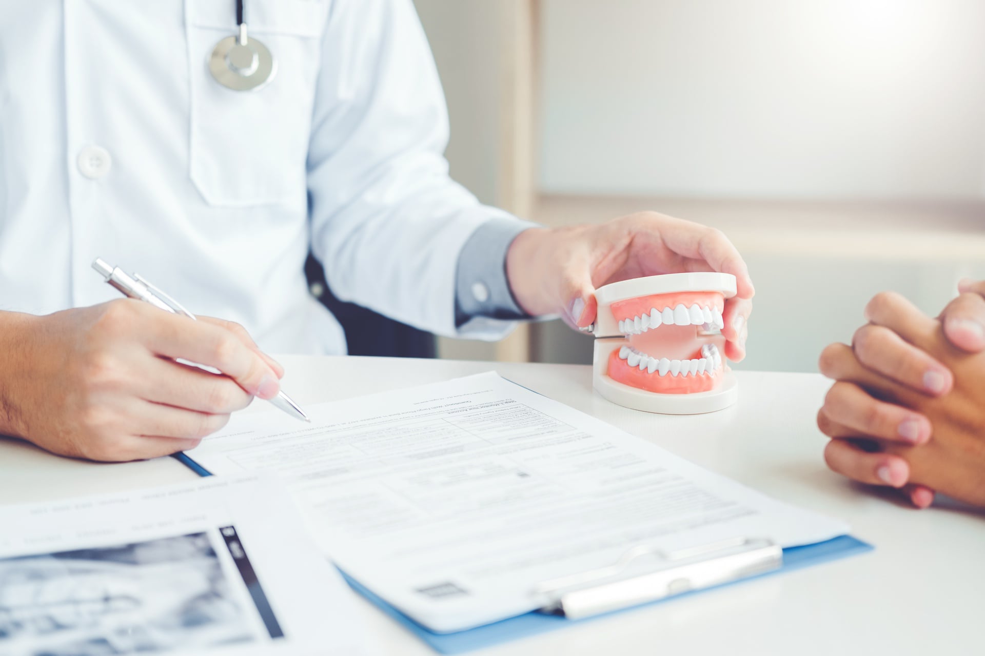 Dentist showing a dental model to a patient while explaining treatment plan and cost estimate during consultation at Affinity Dental Clinics