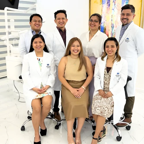 Group photo of the dentists of Affinity Dental Clinics Cebu, smiling inside one of the clinic’s modern treatment suites with bright interiors and dental equipment in the background.