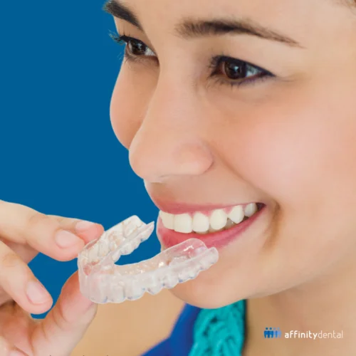 Smiling woman holding a clear dental retainer – promoting clear retainers after braces