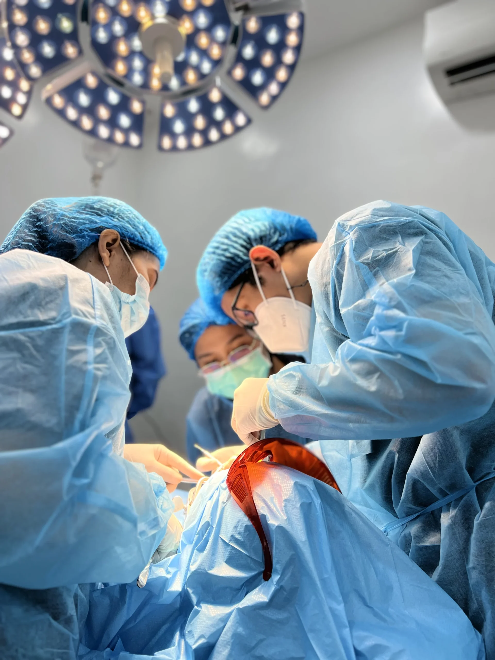 Medical surgeons performing surgery in sterile operating room with surgical lights and equipment